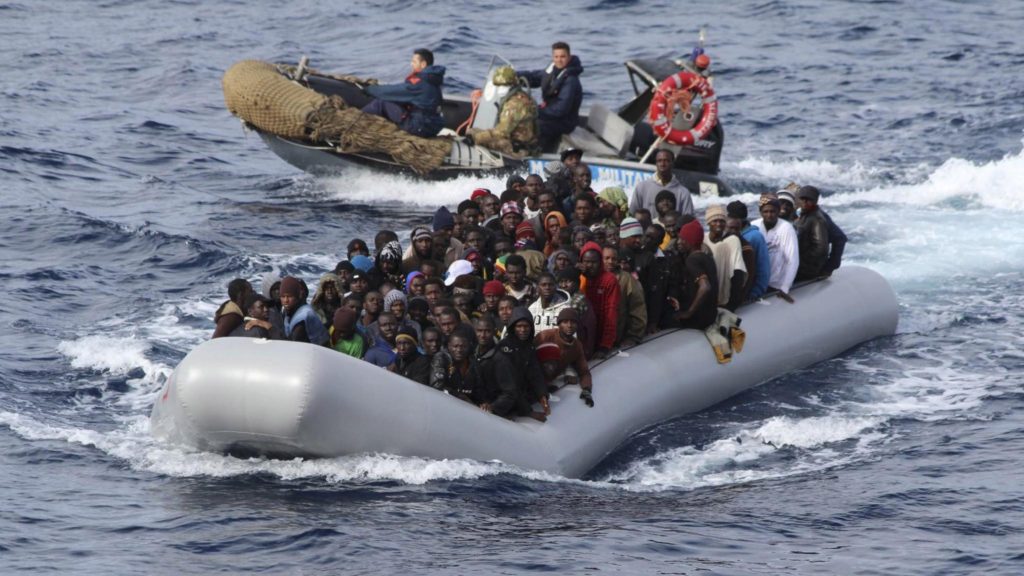 Migrants sit in a boat during a rescue operation by Italian navy off the coast of the south of the Italian island of Sicily