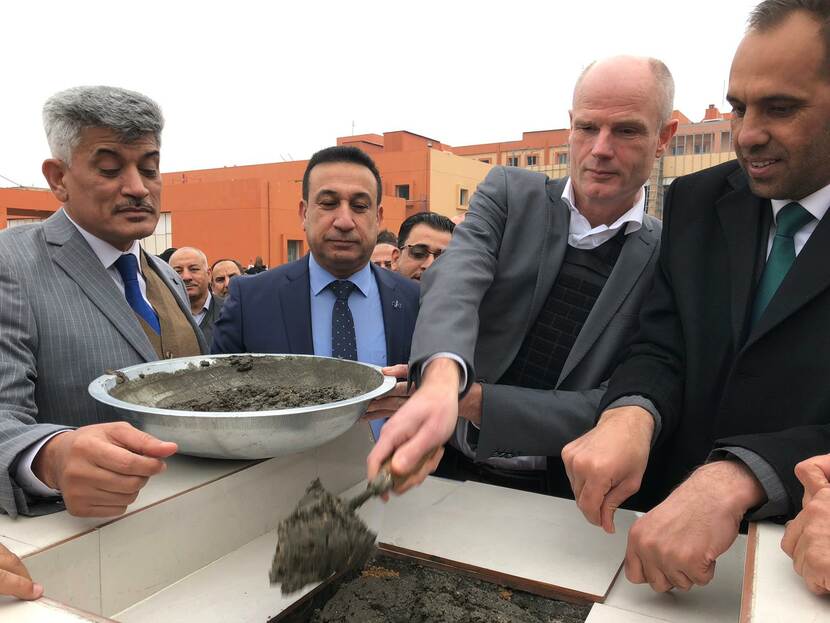 Minister Blok metselt een steen bij de heropening van het Fallujah Teaching Hospital