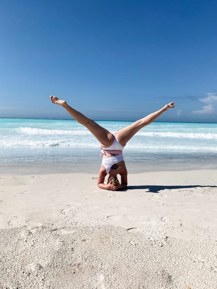 woman in white tank top and white shorts jumping on beach during daytime