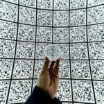 person holding clear glass ball with QR code background