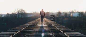 man walking in the middle of rail road