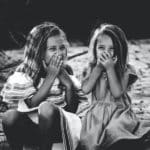grayscale photography of two girls closing their mouths